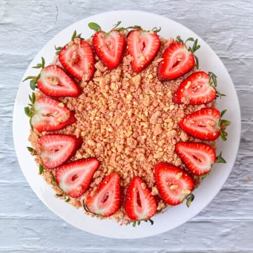 Overhead view of an entire no-bake strawberry cheesecake topped with strawberry crunch and cut strawberries