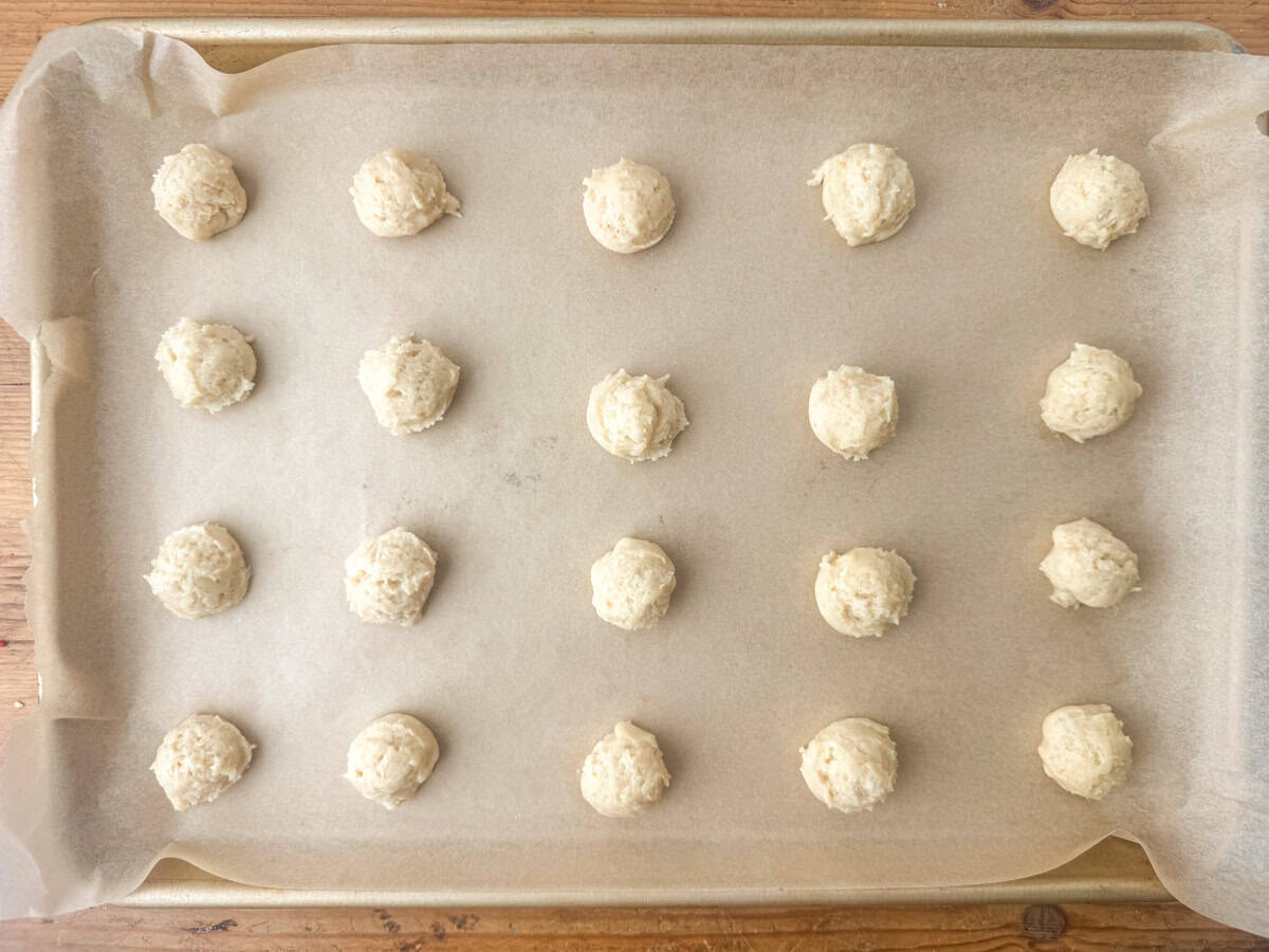 Overhead view of uncooked sour cream sugar cookies on a cookie sheet