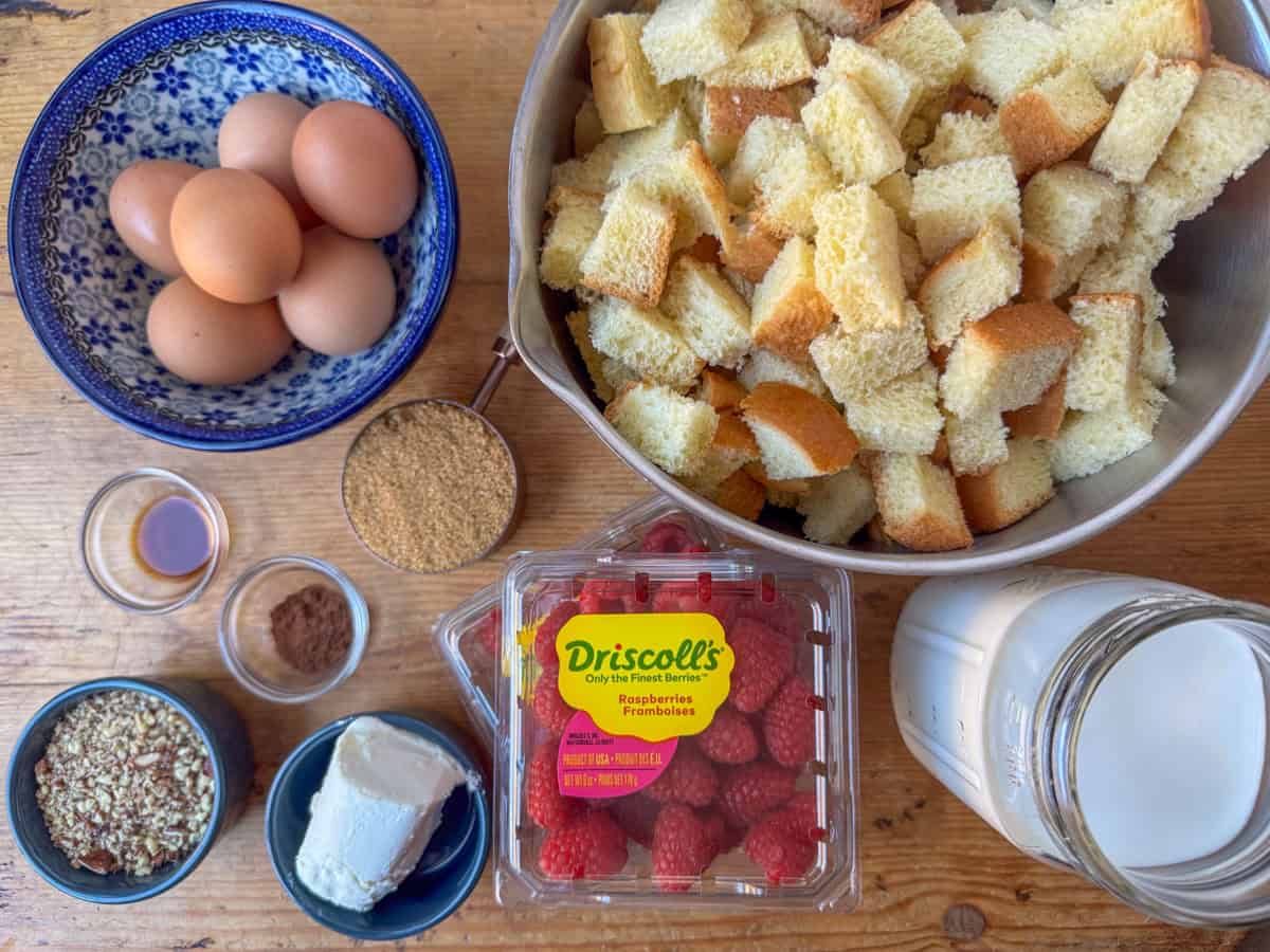 Ingredients needed to make baked raspberry brioche French Toast: cubed brioche bread, raspberries, goat cheese, pecan pieces, eggs, whole milk, brown sugar, vanilla and cinnamon.  