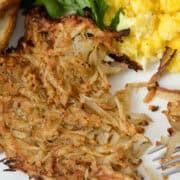 Overhead view of a partially eaten hash brown next to eggs, toast and parsley garnish