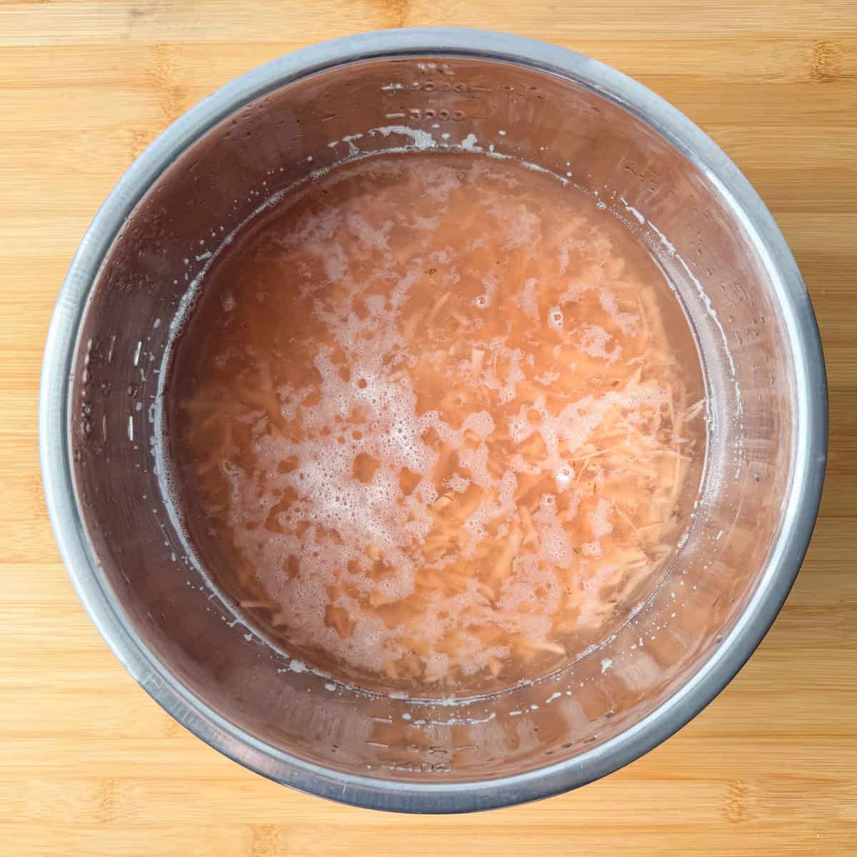 Overhead view of grated potatoes soaking in water