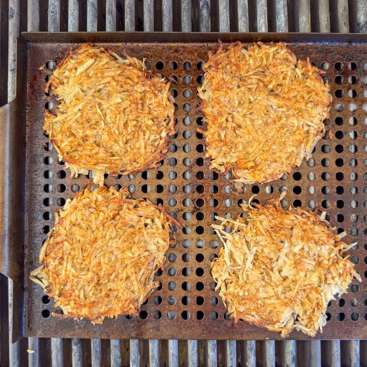 Overhead view of hash brown patties cooking on a grill