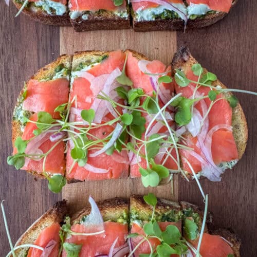 Overhead close up view of sliced smoked salmon bruschetta pieces on a cutting board