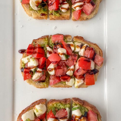 Overhead view of caprese bruschetta with olive oil and balsamic cream drizzle on a serving plate
