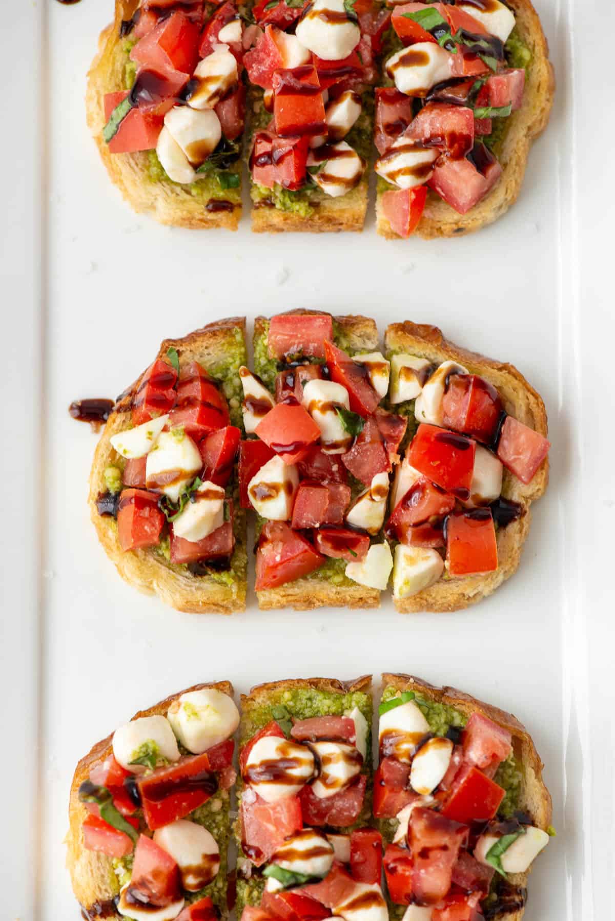 Overhead view of caprese bruschetta with olive oil and balsamic cream drizzle on a serving plate