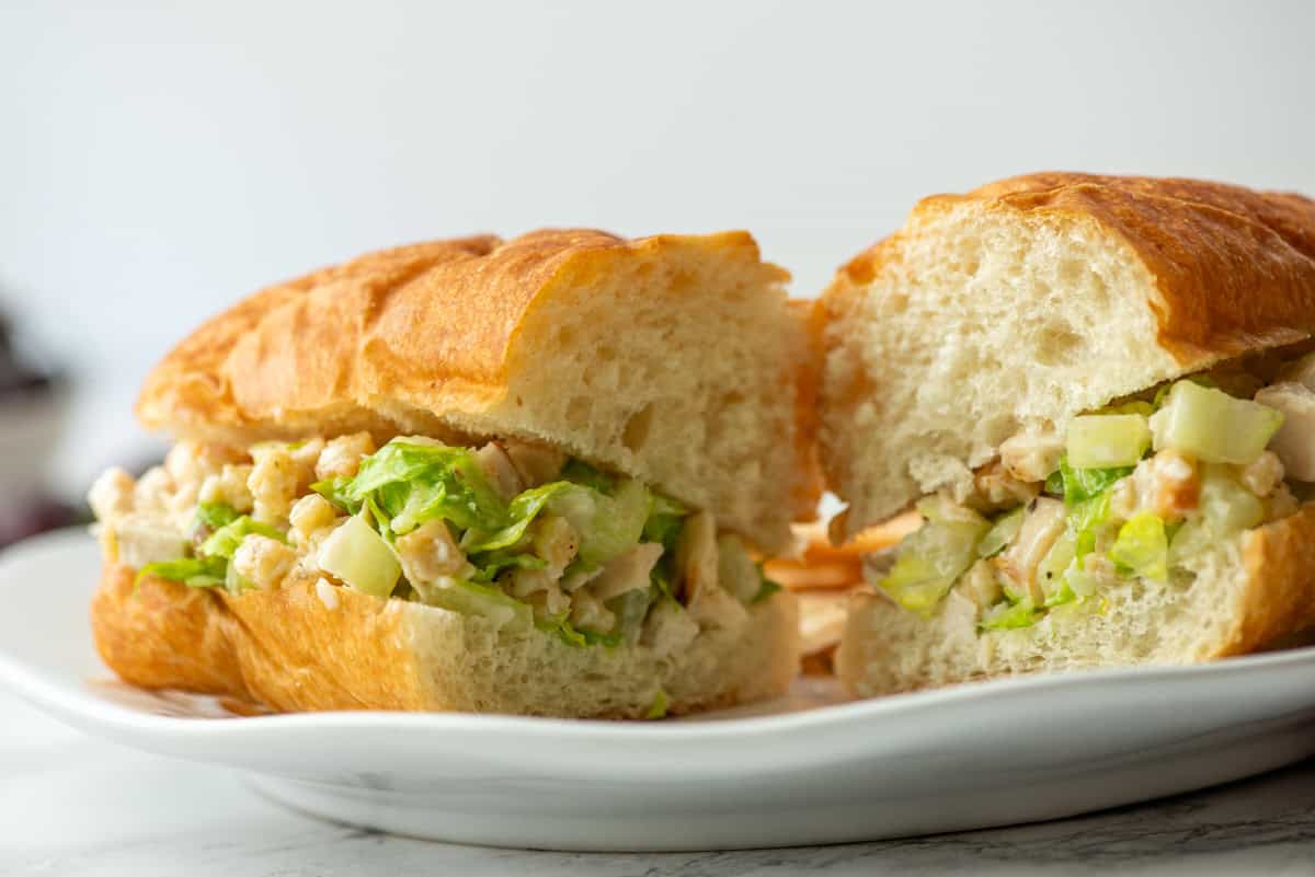 Side view of a cut and split chicken caesar salad sandwich on a hoagie roll