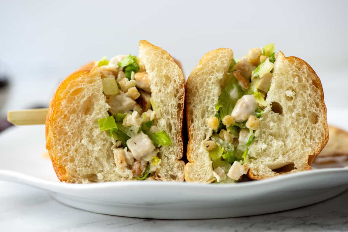 Side view of a cut chicken caesar salad sandwich that was flipped so that you can see the cut side of both pieces