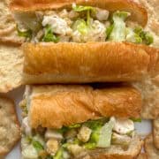 Overhead view of a cut chicken caesar salad sandwich that's been turned on it's side and is surrounded by pita style chips