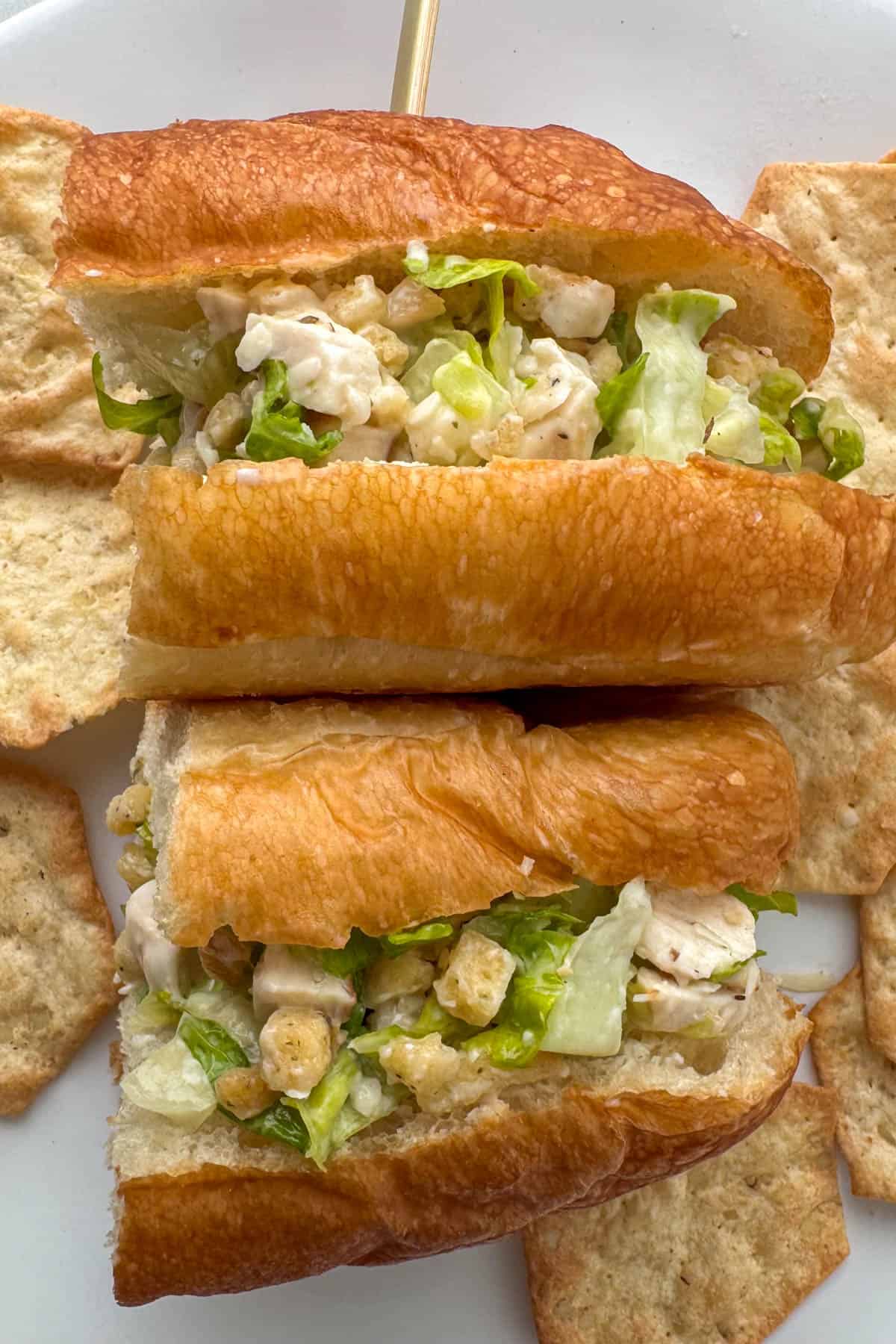 Overhead view of a cut chicken caesar salad sandwich that's been turned on it's side and is surrounded by pita style chips