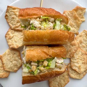 Overhead view of a cut chicken caesar salad sandwich that's been turned on it's side and is surrounded by pita style chips