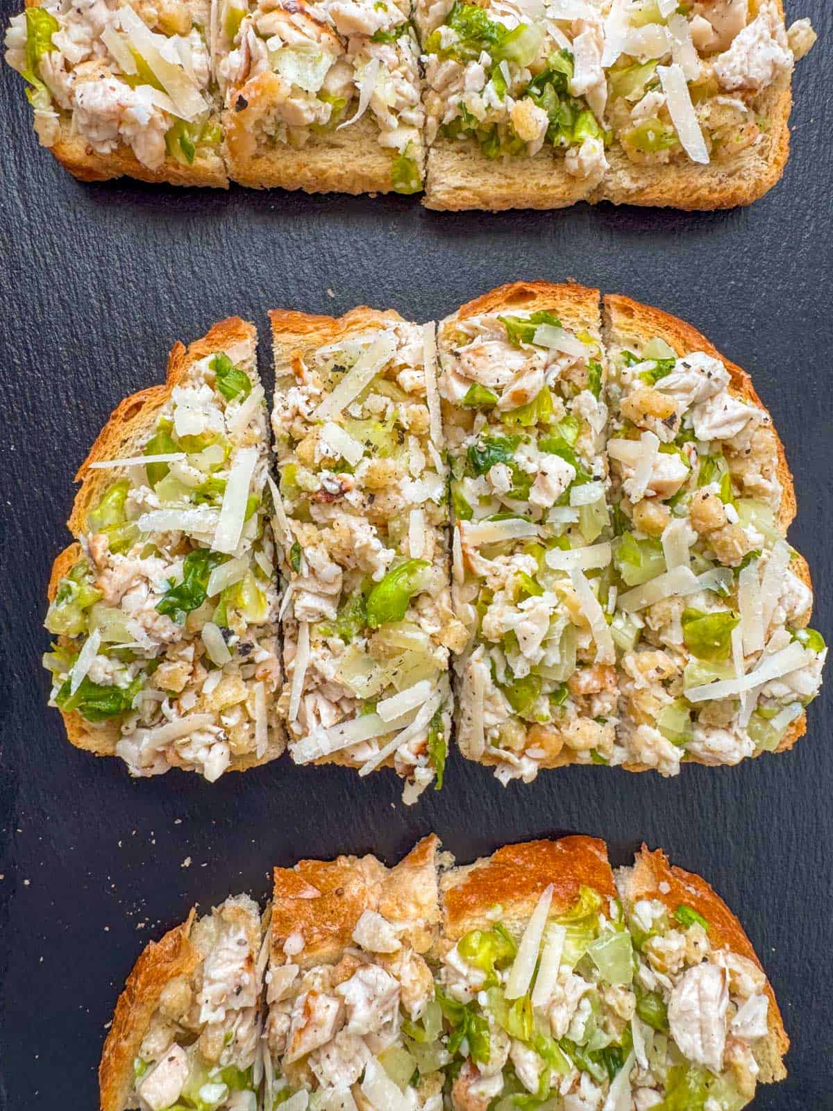 Chicken caesar salad bruschetta on full size sourdough bread with each piece cut into four pieces