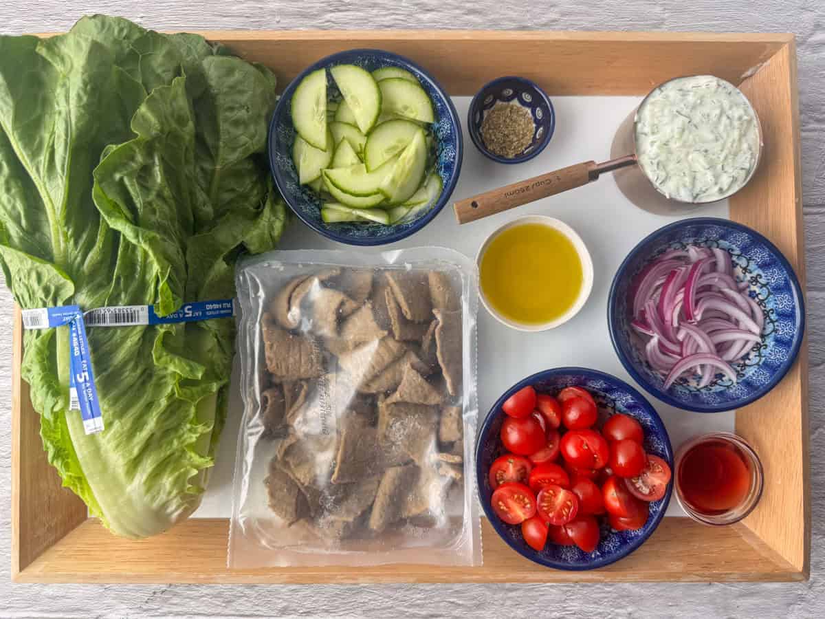 Ingredients needed for a gyro salad: gyro meat, romaine lettuce, sliced cucumber, cherry tomatoes, red onion, tzatziki sauce, olive oil, red wine vinegar and oregano
