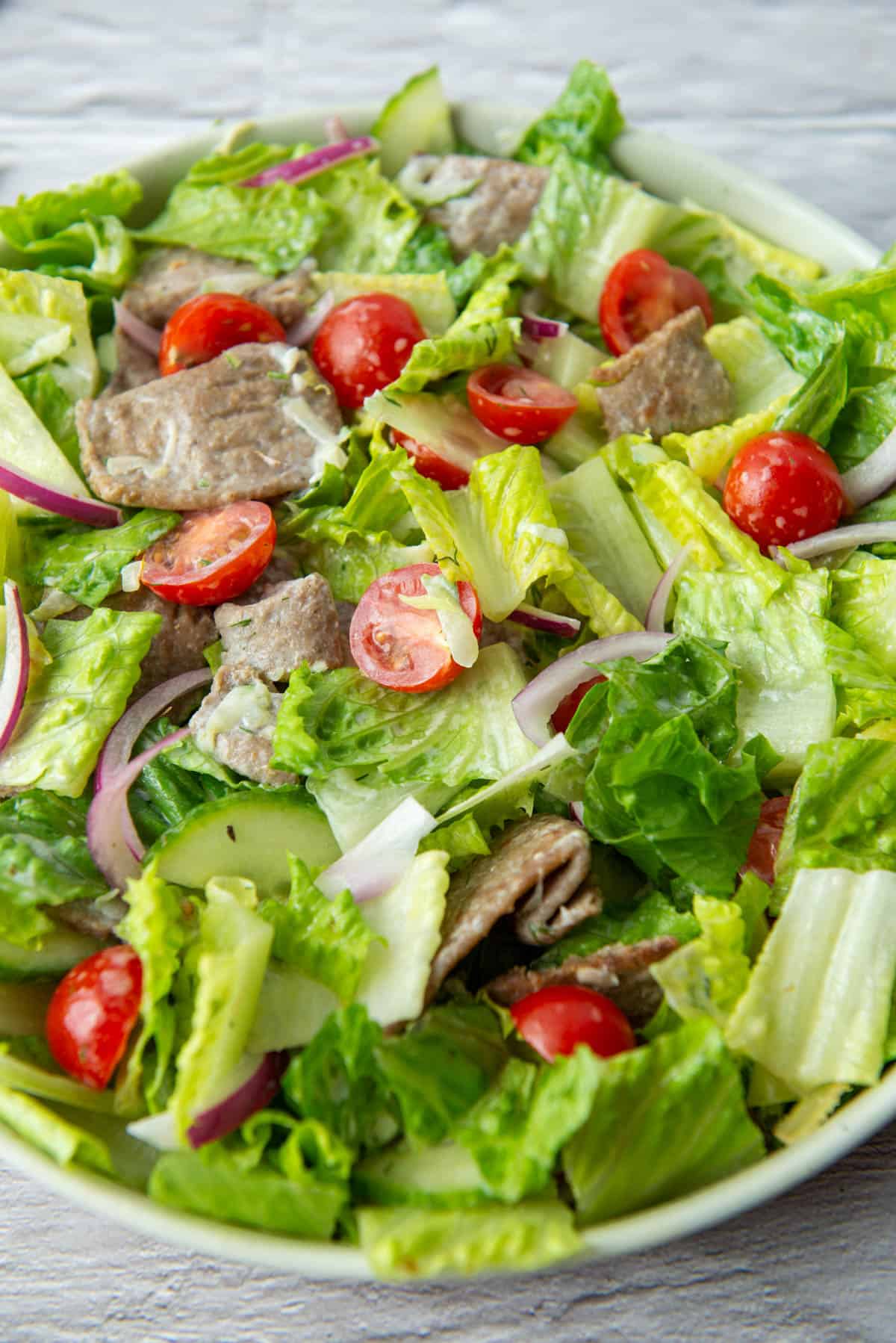 Overhead view of a gyro salad where the ingredients including the tzatziki sauce have all been mixed together