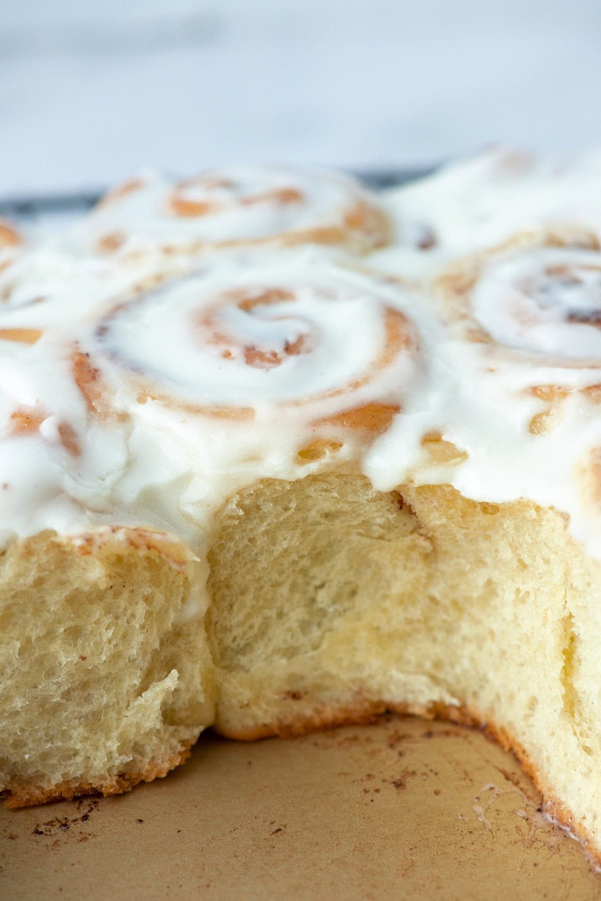 Side view into a baking pan of mini cinnamon rolls with some missing so that you can see the  sweet dough layers