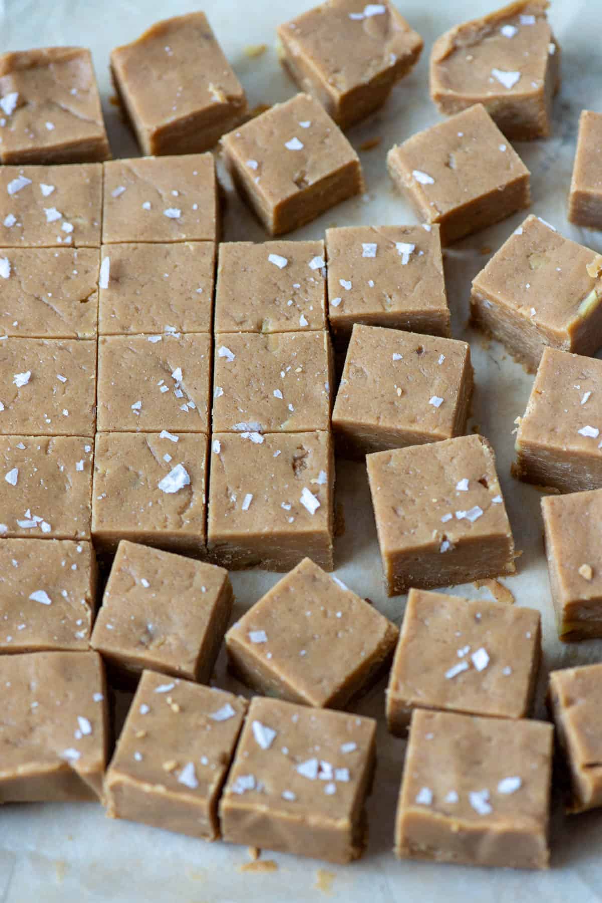 Cut peanut butter fudge squares topped with salt flakes on parchment paper