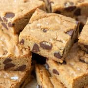 Randomly stacked brown butter chocolate chip cookie bars on a white plate