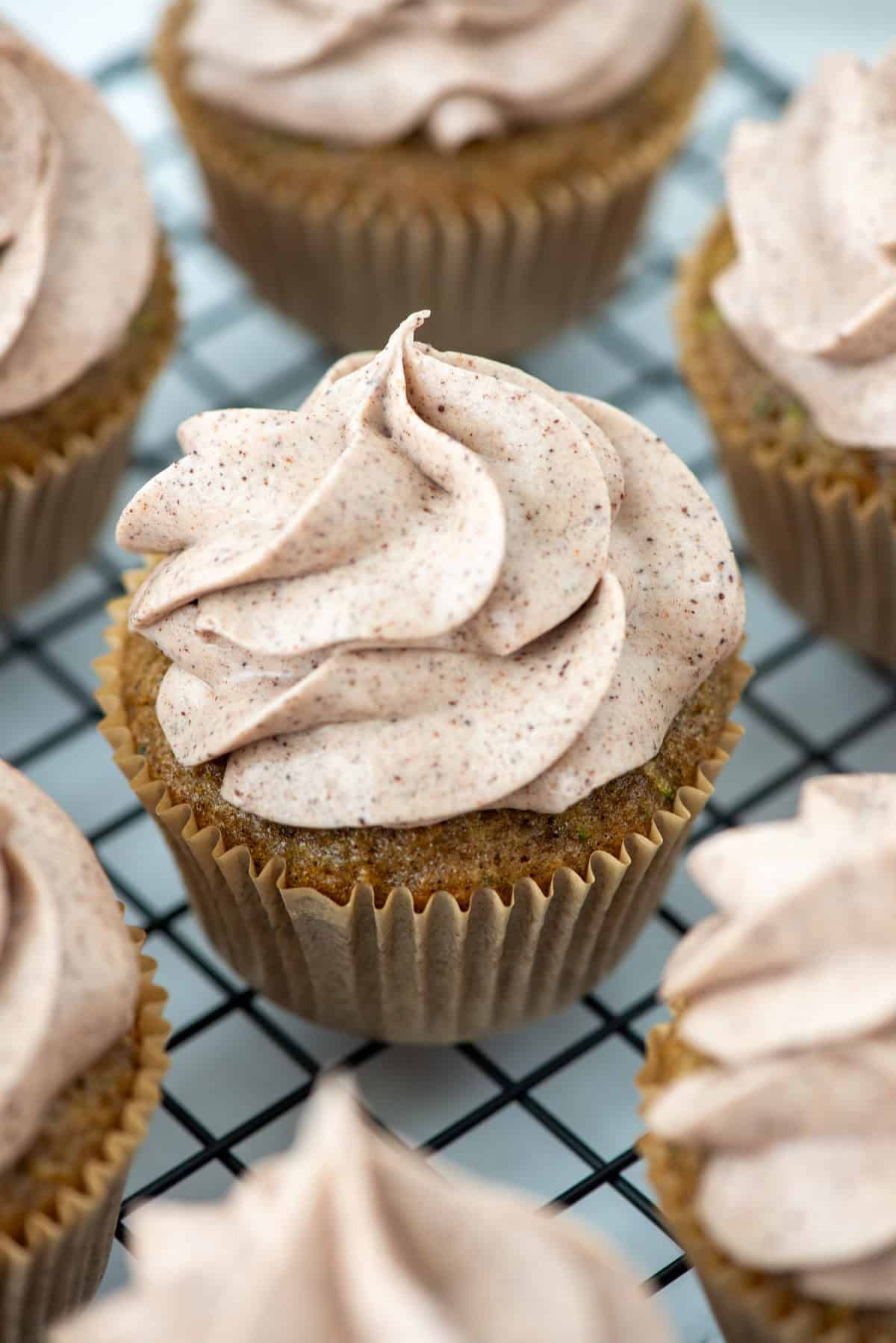 Close up view of zucchini cupcakes with cinnamon cream cheese frosting on a cooling rack