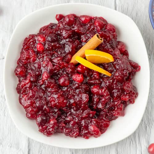 Overhead view of a bowl of Grand Marnier cranberry sauce garnished with orange slices and a cinnamon stick