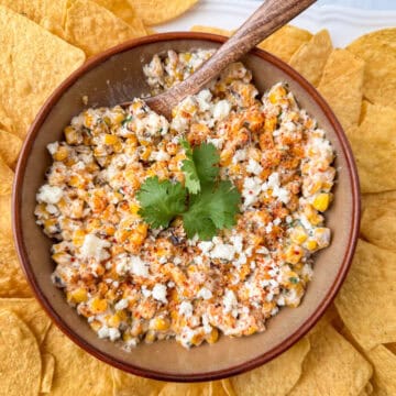 Overhead view of a bowl of Mexican Street Corn dip garnished with cilantro surrounded by tortilla chips