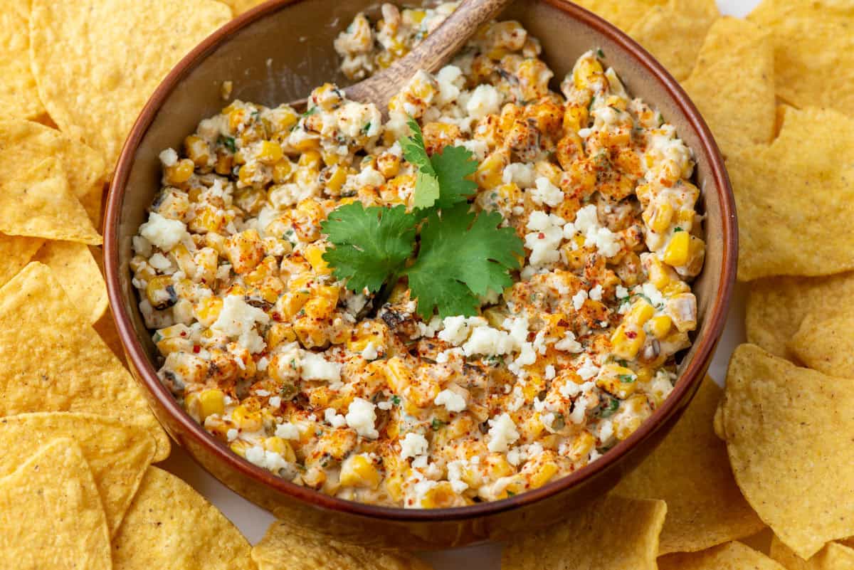 Overhead view of a bowl of Mexican Street Corn dip garnished with cilantro with tortilla chips