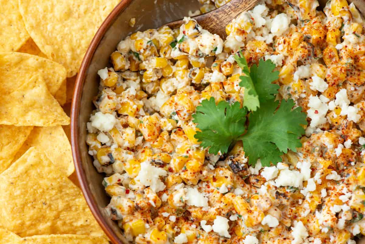 Overhead view of a bowl of Mexican Street Corn dip garnished with cilantro with tortilla chips