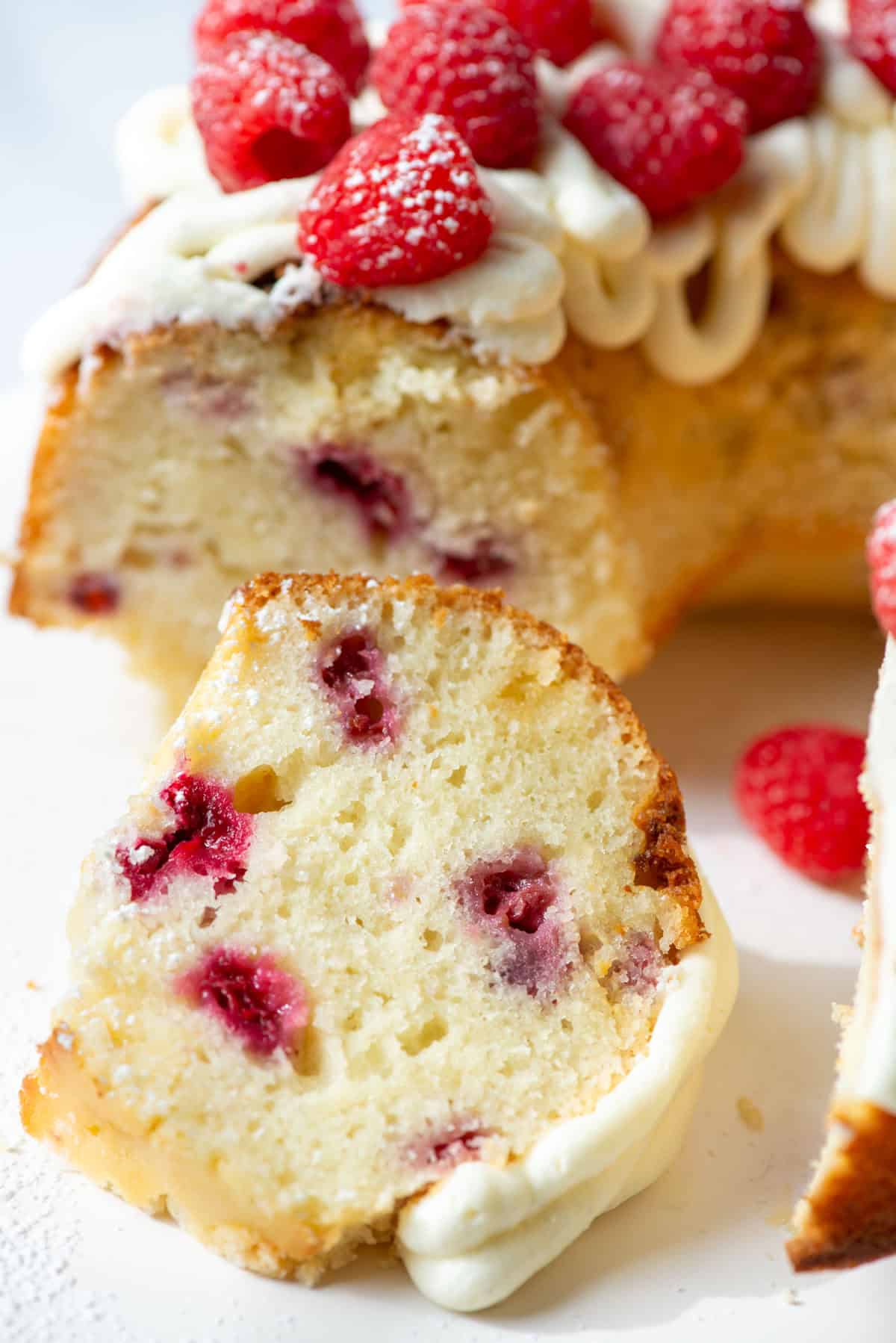 Overhead view of a slice of white chocolate raspberry bundt cake next to a partial view of the rest of the cake
