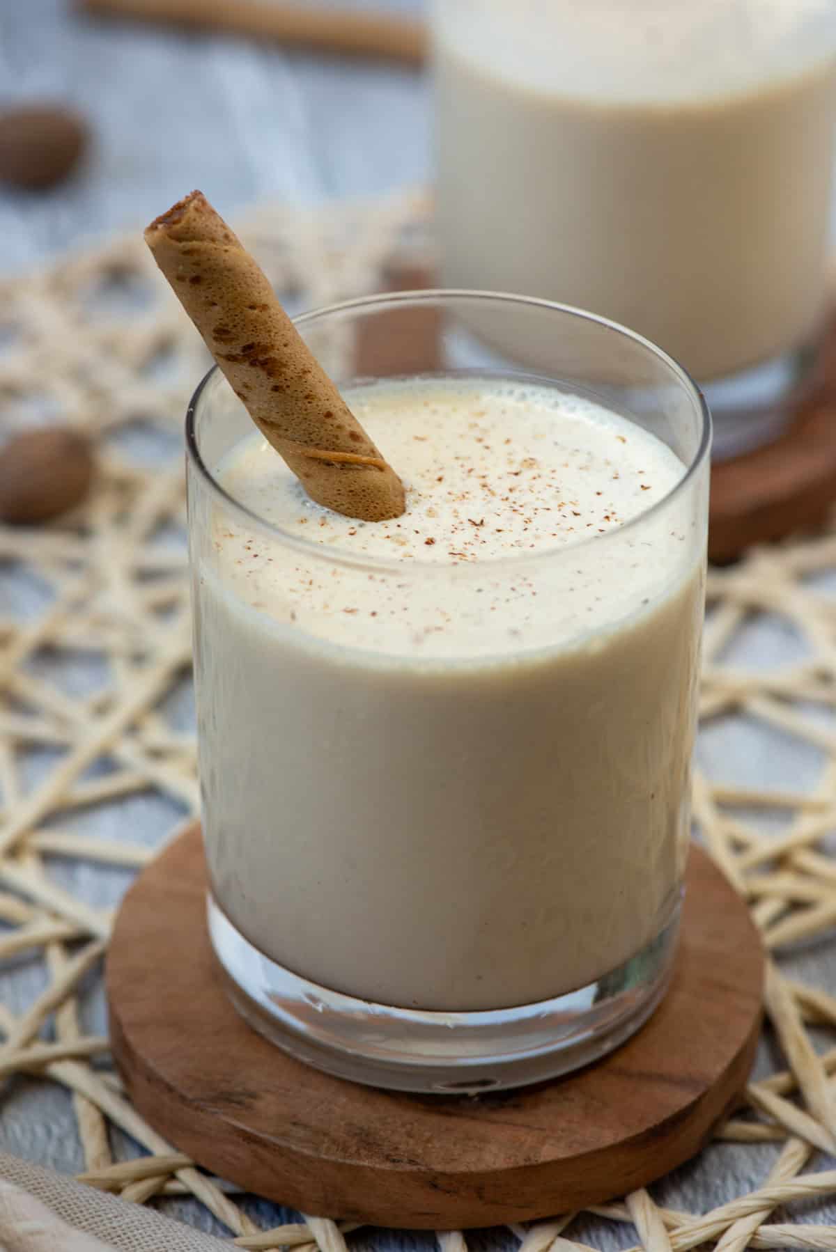 Close up of one frozen Brandy Alexander cocktail in a lowball glass with fresh grated nutmeg on top and a Pirouette cookie as a stir stick