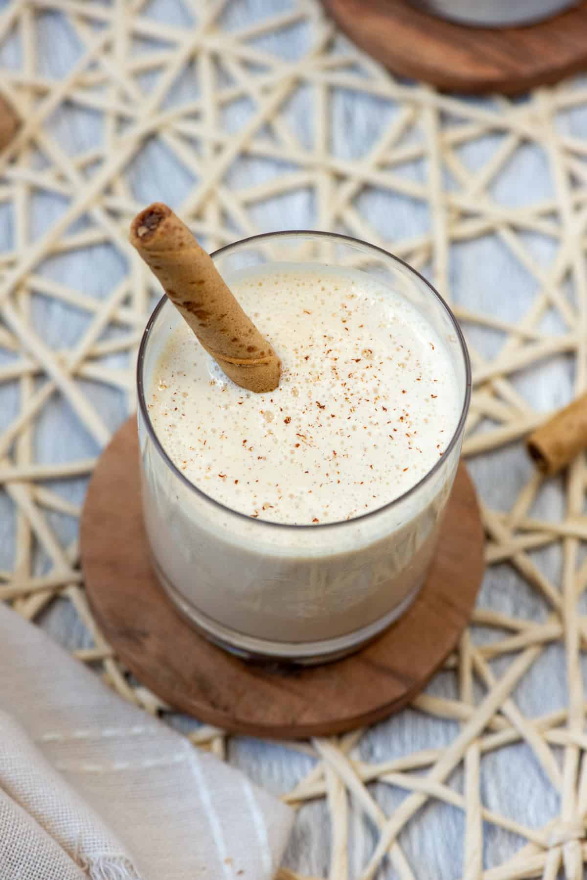 Overhead view of one frozen Brandy Alexander cocktail in a lowball glass with fresh grated nutmeg on top and a Pirouette cookie as a stir stick