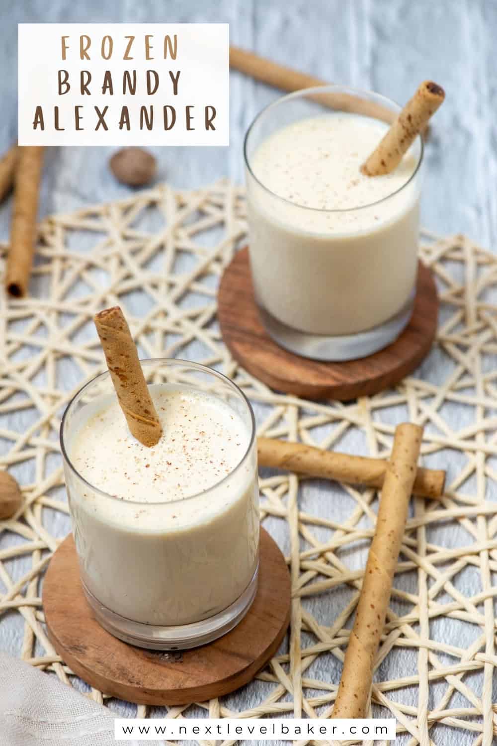 Frozen Brandy Alexander cocktails garnished with ground nutmeg and Pirouette cookies. Photo has a Frozen Brandy Alexander title overlay and www.nestlevelbaker.com overlay at the bottom