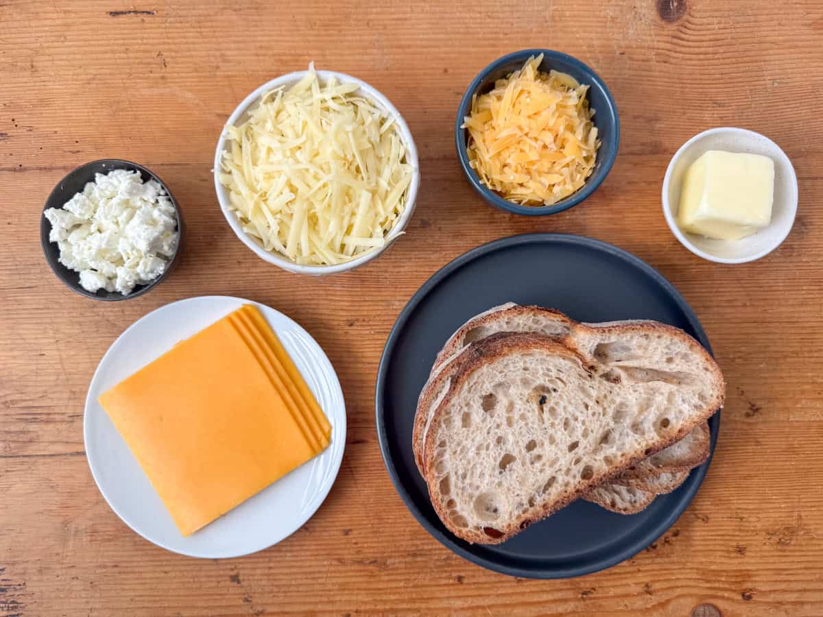 Ingredients needed to make four cheese grilled cheese: good bread, salted butter, sliced cheddar cheese, gruyere cheese, gouda cheese and goat cheese.