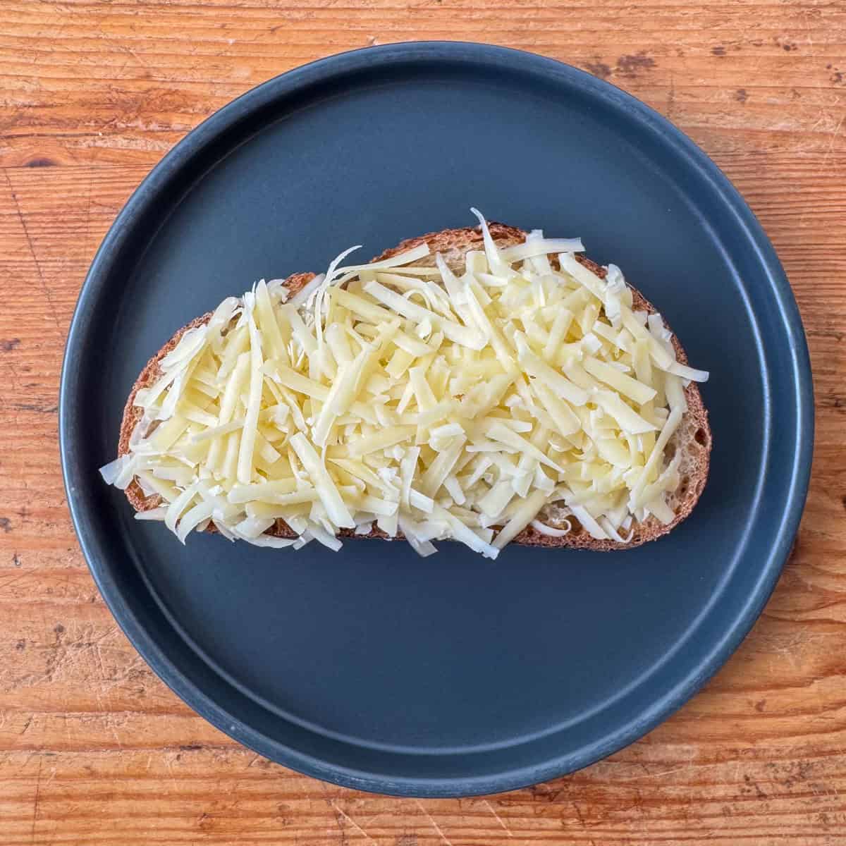 Step 1 of making a four cheese grilled cheese: adding the grated gruyere cheese