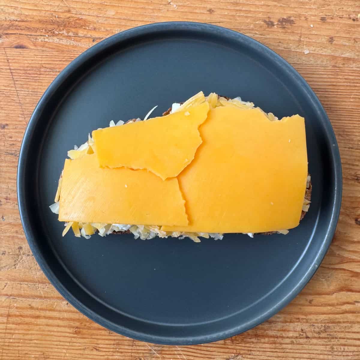 Step 4 of making a four cheese grilled cheese: add a single layer of cheddar cheese