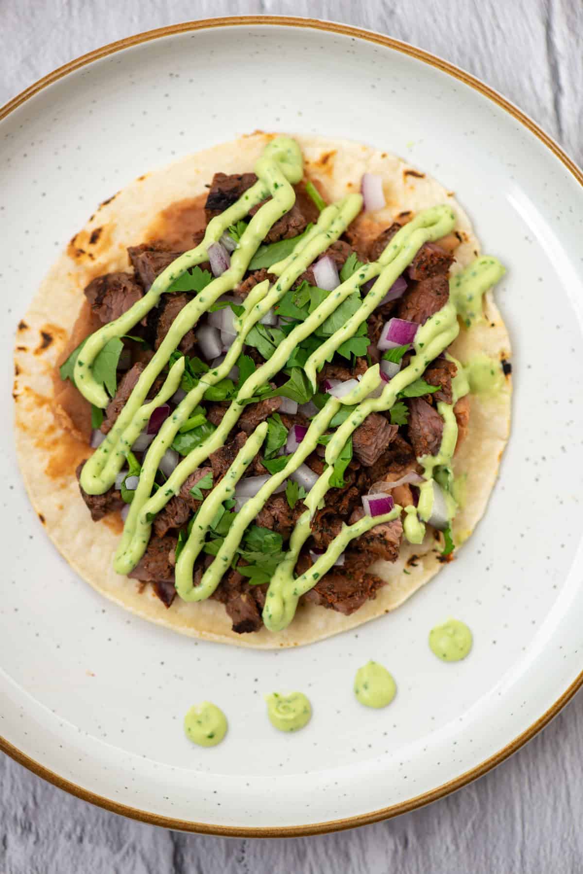 Overhead photo of a tostado drizzled with Avocado Lime Crema on top