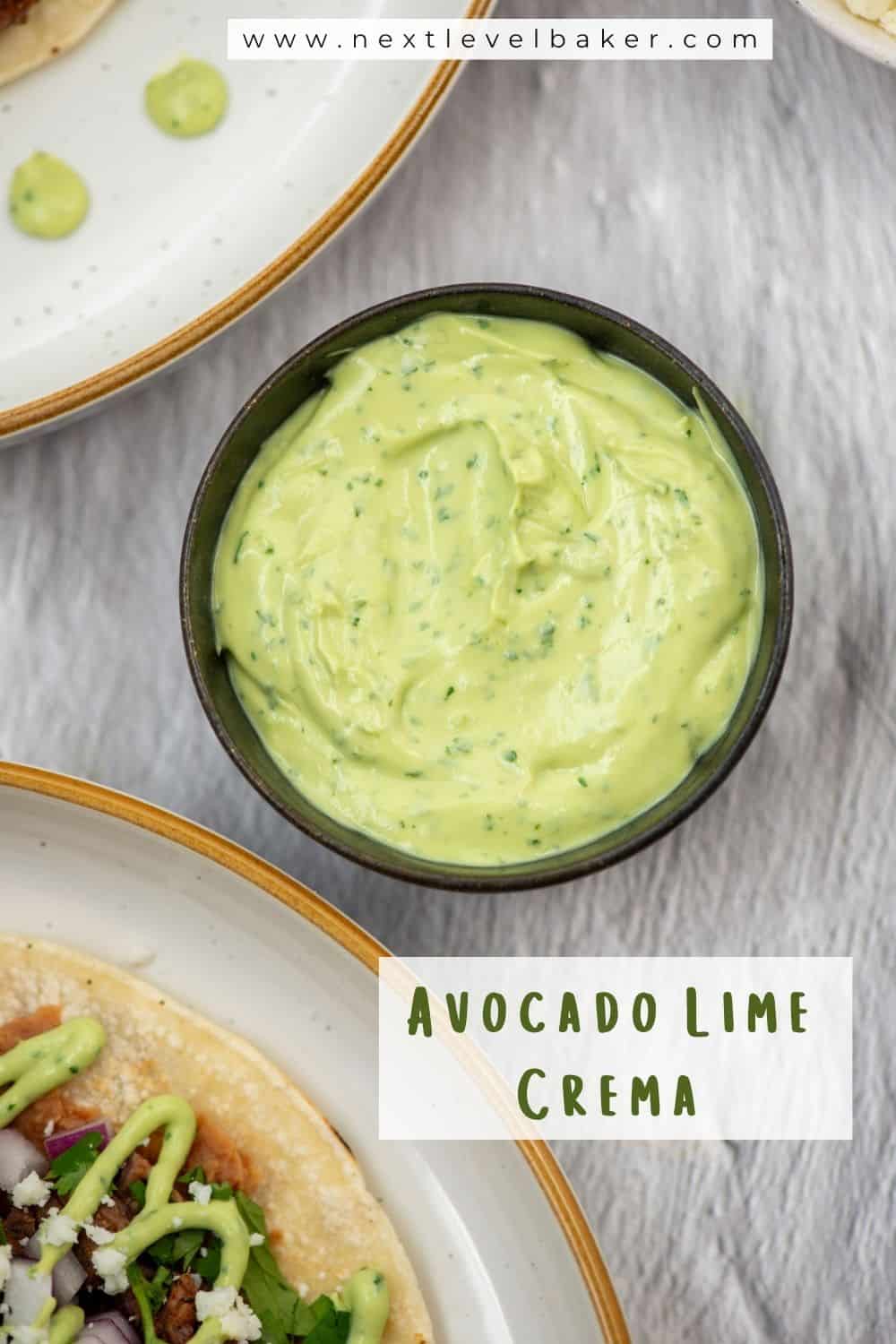 Overhead photo of a small sauce cup of avocado lime crema next to two plates of tostados with avocado lime crema drizzled on top with a title overlay that says Avocado Lime Crema and another title overlay that says www.nextlevelbaker.com