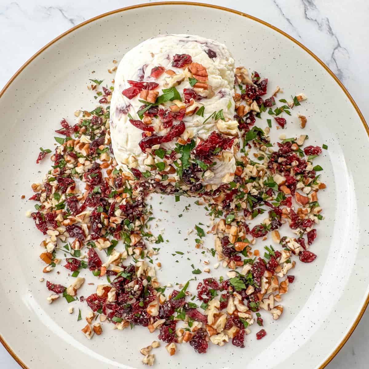 Step 5: Shape chilled cheeseball while it's still in the plastic wrap. Then remove plastic wrap and roll in pecan, cranberry and parsley mixture.