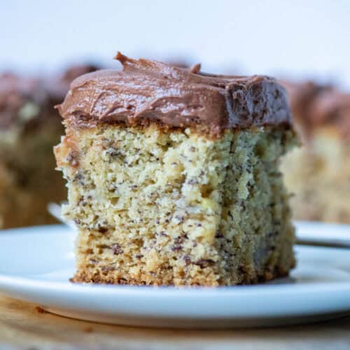 Close up, side view of one slice of gluten free banana cake on a plate with the rest of the cake in the background