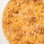 Overhead, close up view of a partial pumpkin pecan cheesecake with a title overlay that says Pumpkin Pecan Cheesecake and another one that says www.nextlevelbaker.com