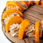 Overhead view of a partial orange chocolate cheesecake garnished with orange chocolate ganache, orange chocolate whipped cream and fresh orange slices with a title overlay that says Orange Chocolate Cheesecake