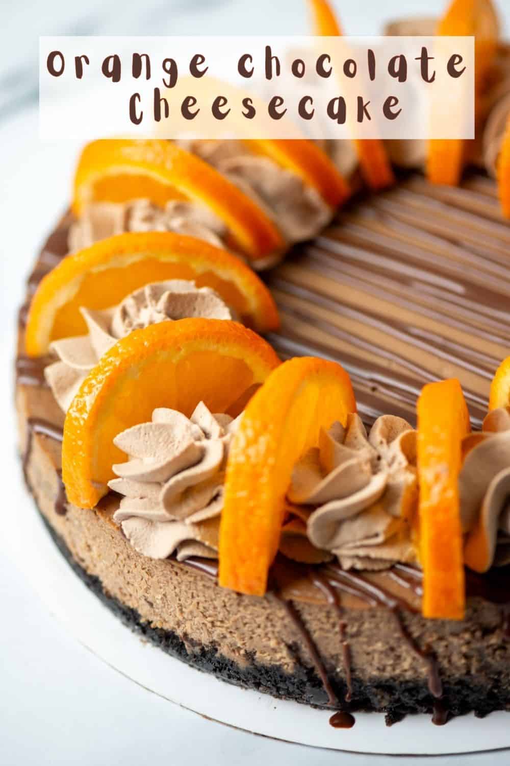 Overhead view of a partial orange chocolate cheesecake garnished with orange chocolate ganache, orange chocolate whipped cream and fresh orange slices with a title overlay that says Orange Chocolate Cheesecake
