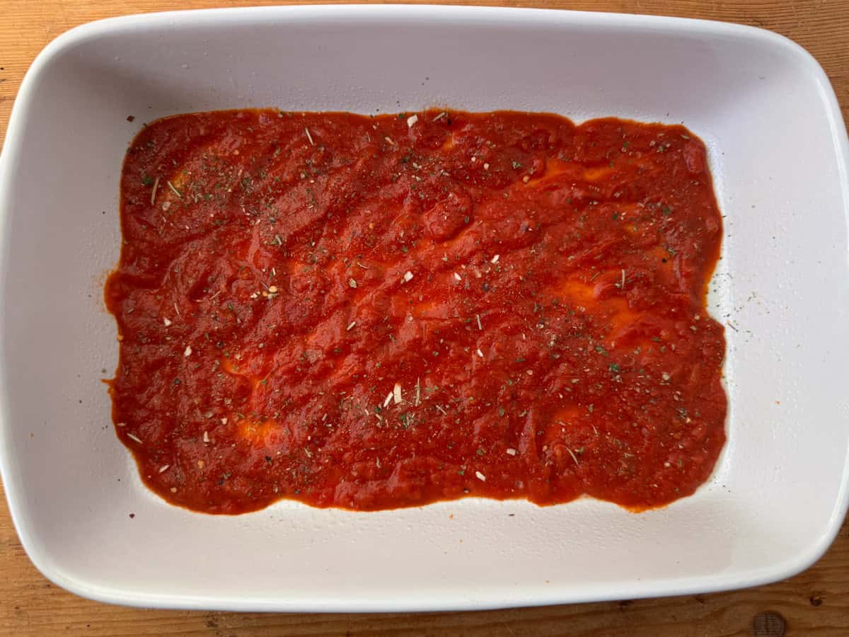 Step 1 of layering veggie lasagna: Spray a 9x13 baking dish with cooking spray and spread one cup of marinara or pasta sauce on the bottom of the baking pan