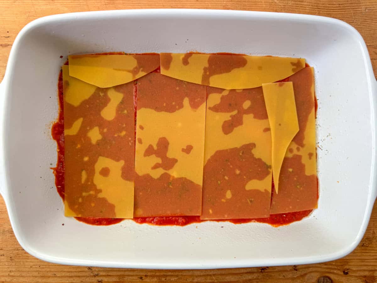 Step two of making lasagna: add a layer of lasagna noodles