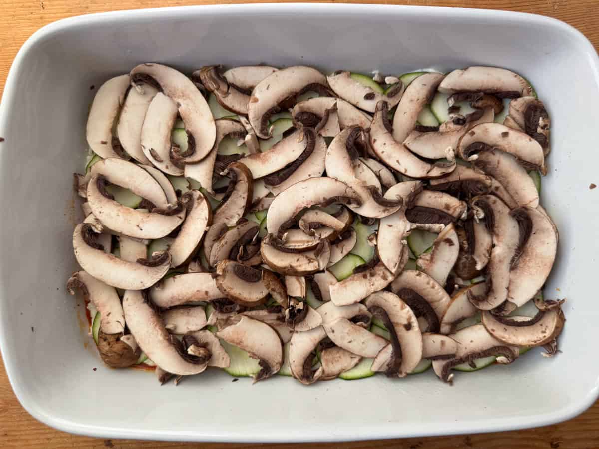 Step 5 of layering lasagna: add a layer of thinly sliced mushrooms