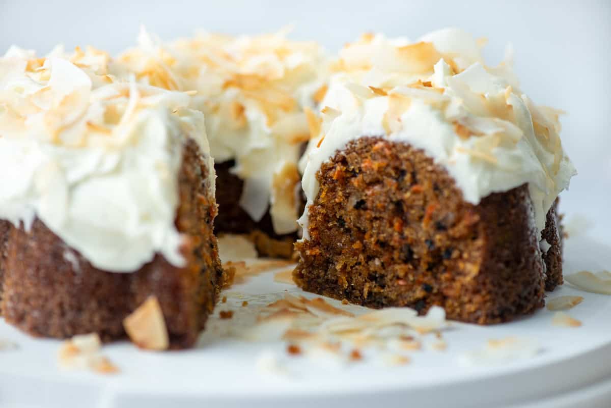 Side view of a carrot bundt cake with a chunk missing so that you can see the insides of the cake