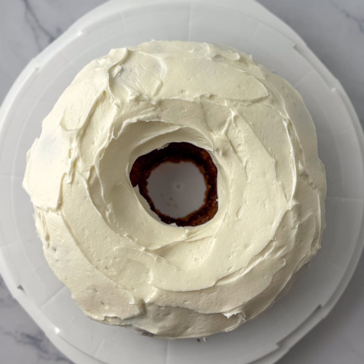 Step two in decorating a carrot bundt cake: smooth out the frosting with a knife or an icing spatula