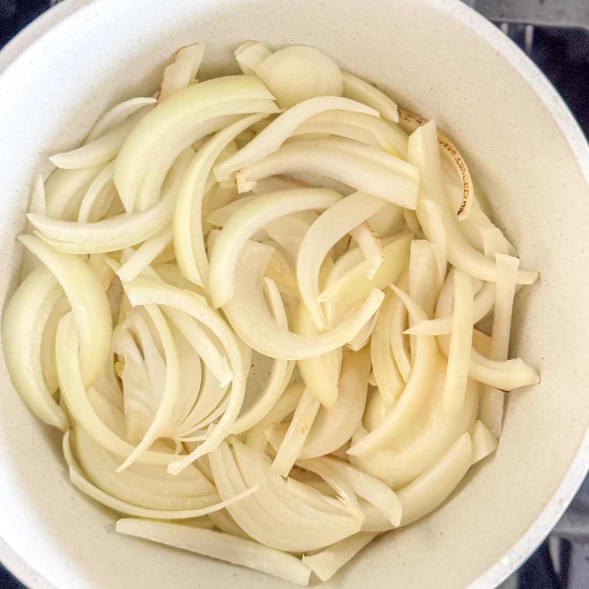 Sliced raw onions in pot as step 1 in the process of caramelization