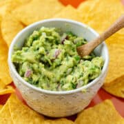 Bowl of four ingredient guacamole surrounded by chips on a plate with a title overlay that says Easy 4 Ingredient Guacamole