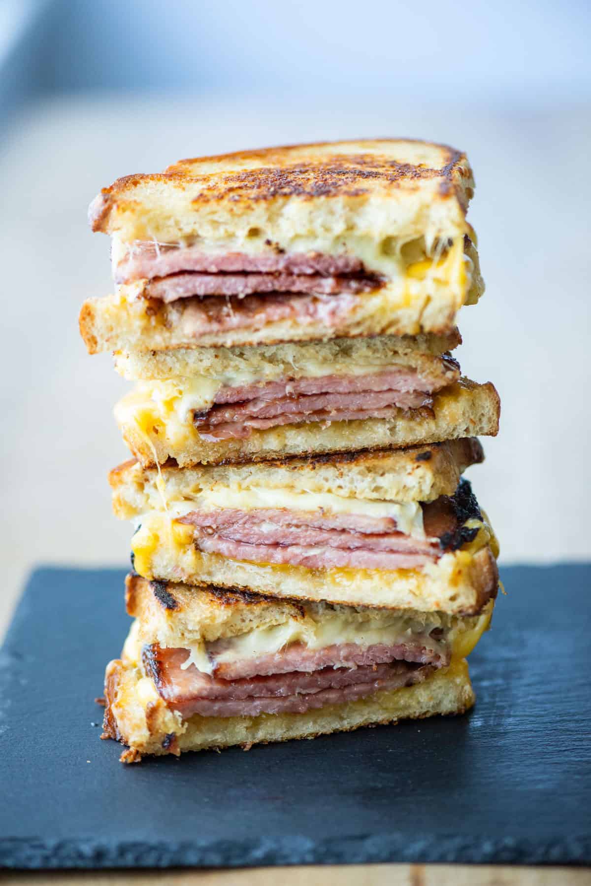 Side view of tall stack of 4 halves of grilled ham sandwiches