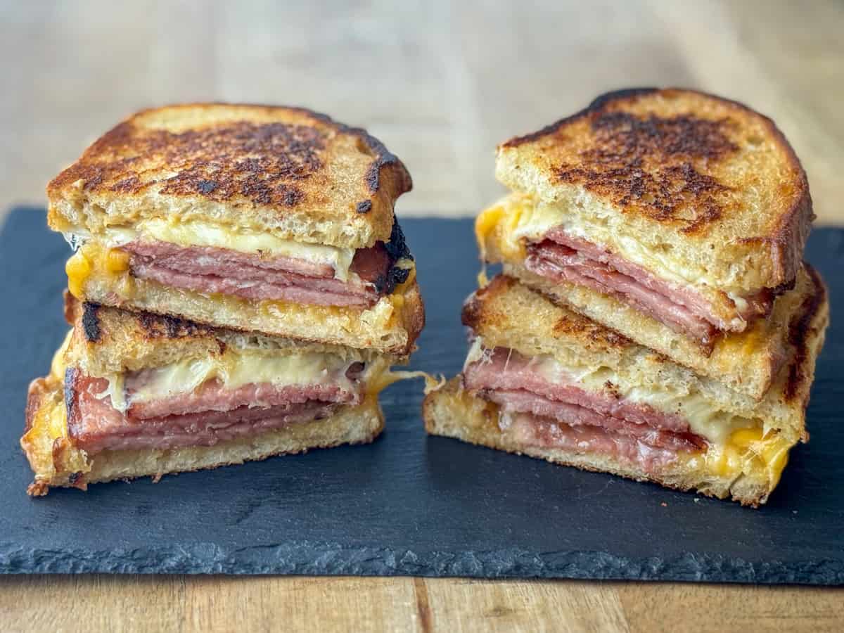Side view of two cut grilled ham and cheese sandwiches on a platter
