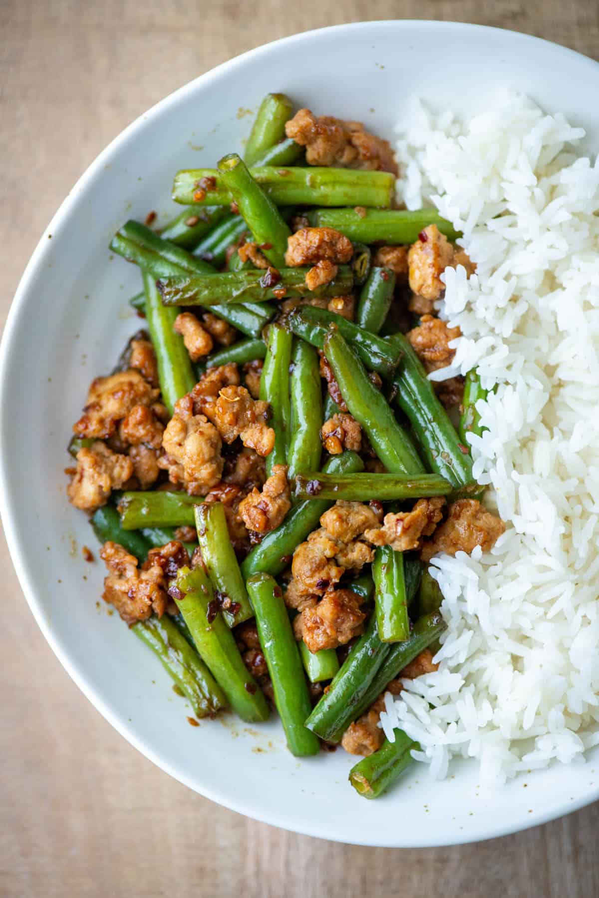 Overhead photo of a partial plate of ground chicken stir fry with green beans on one side and white jasmine rice on the other