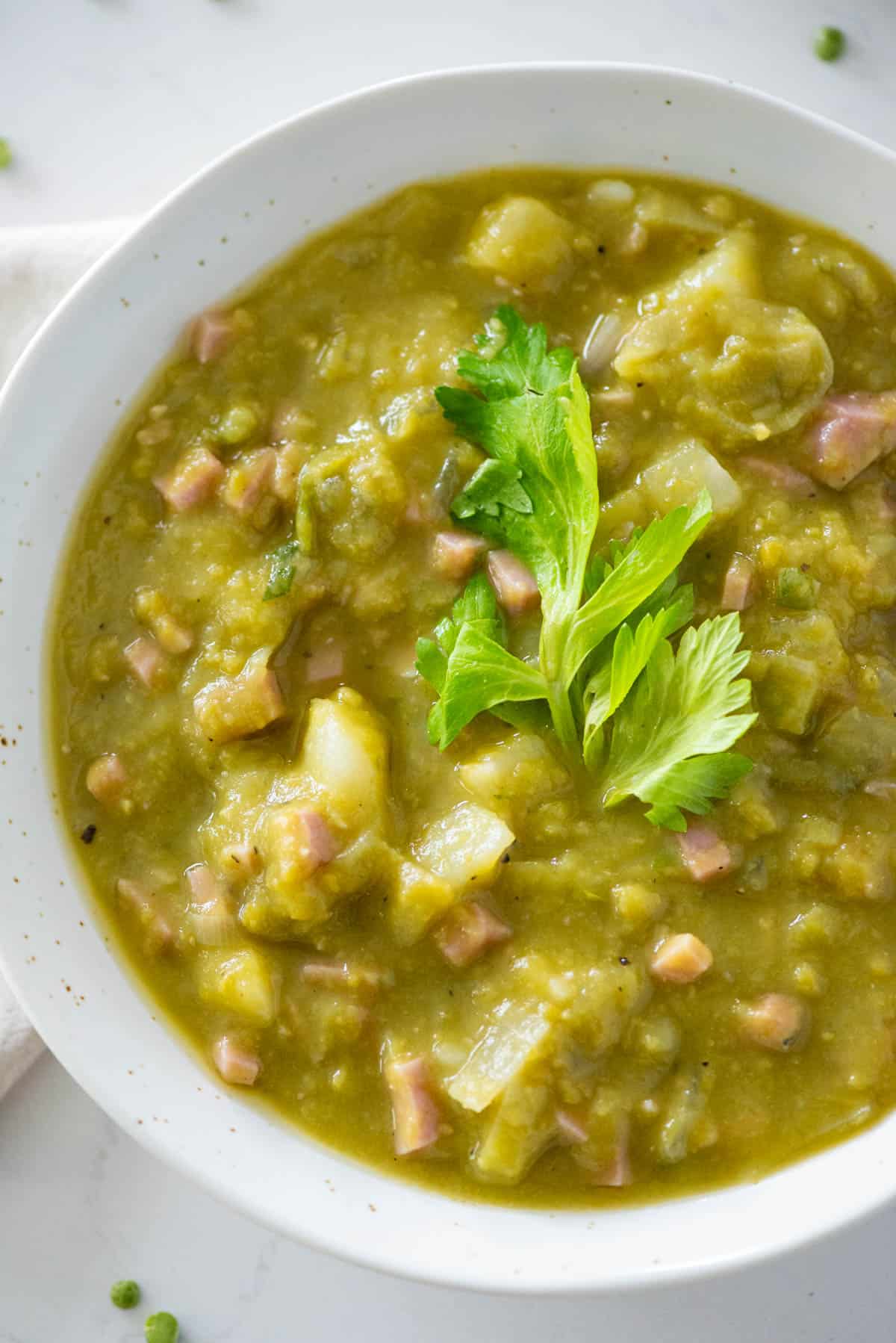 Close up of bowl of split pea soup garnished with celery leaves